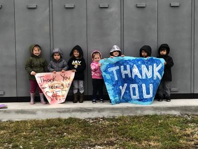Image of 4 children holding two "thank you" signs